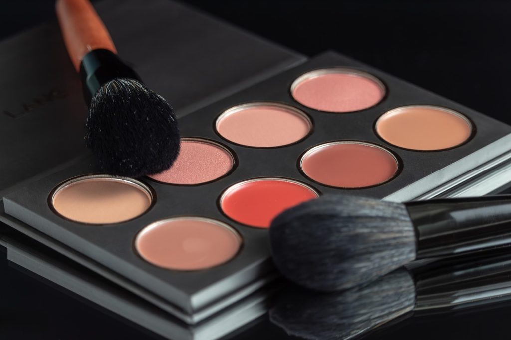 Makeup palette with soft pink and coral shades and two makeup brushes
