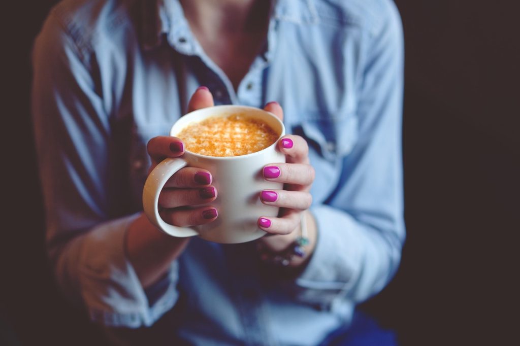 Hands holding a warm mug in a cosy sweater