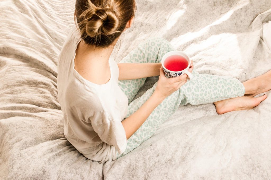 Woman relaxing in bed with a cup of tea on a slow morning