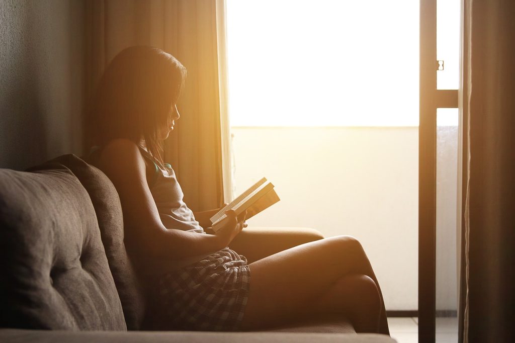 Woman reading quietly by a window in warm light