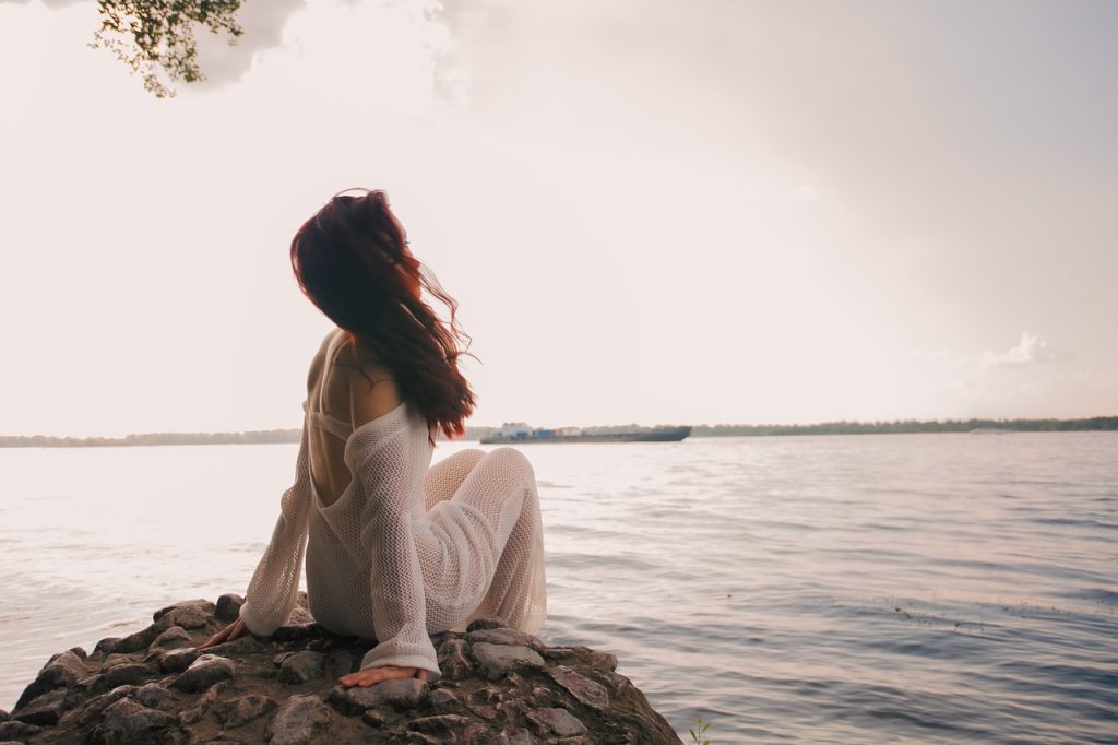 Woman sitting quietly by the sea in soft natural light