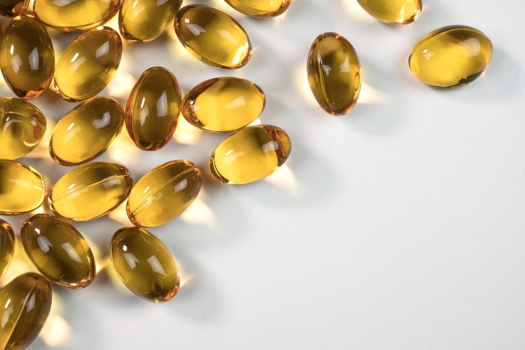 Golden supplement soft gel capsules on a white surface
