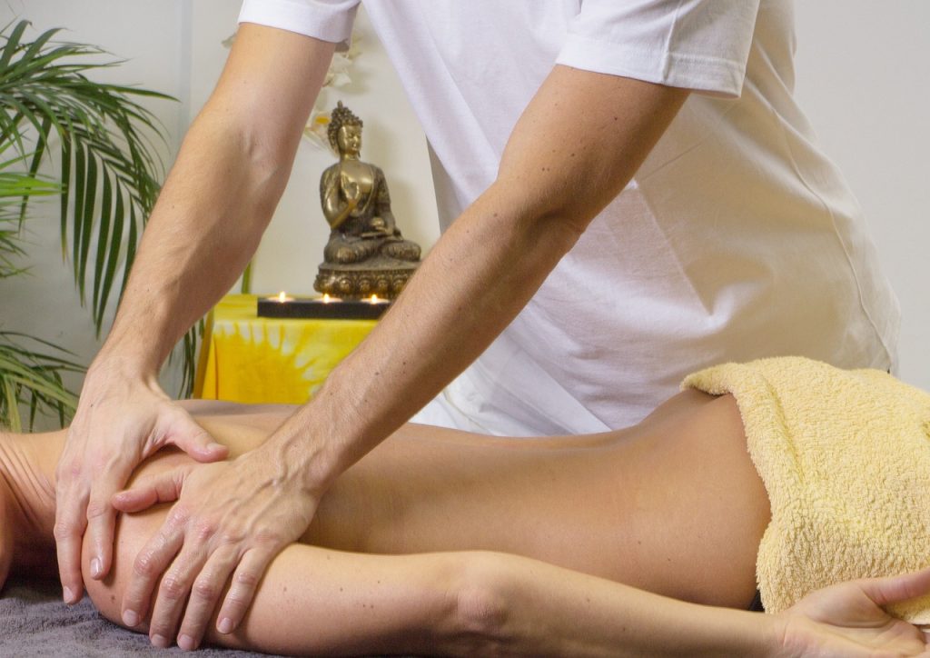 Massage therapist working on tension across a woman's shoulders and upper back